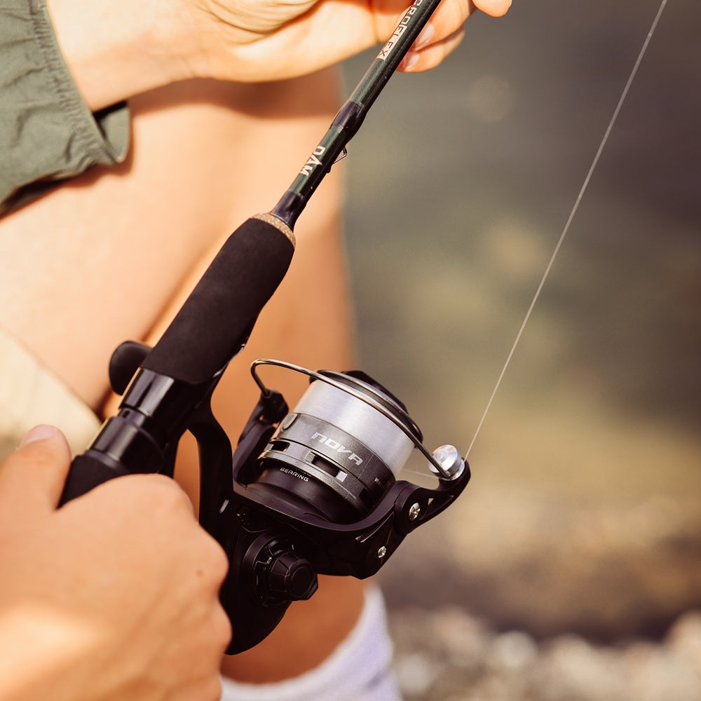 A DAM MicroFlex Rod with a DAM NOVA Spinning Reel  attached, spooled with clear line, being held. The background is blurred.